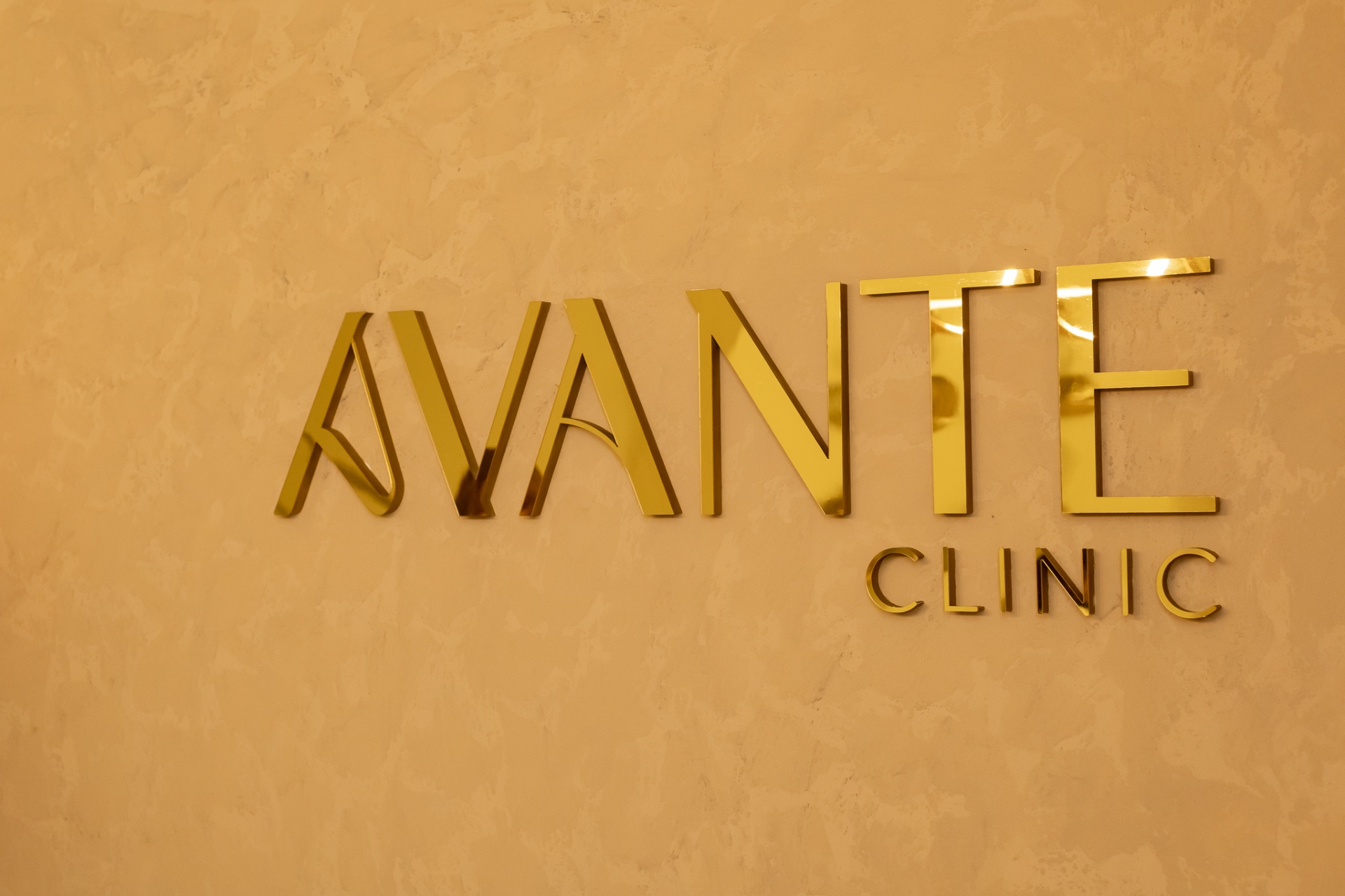 Logo dourado da Avante Clinic na parede da recepção